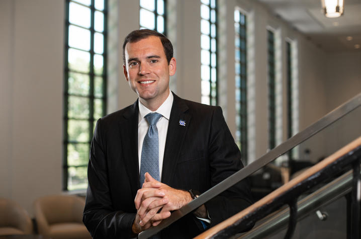 Eric King portrait Eric King wears a suit and poses for a photo along a railing in the Gatton Student Center