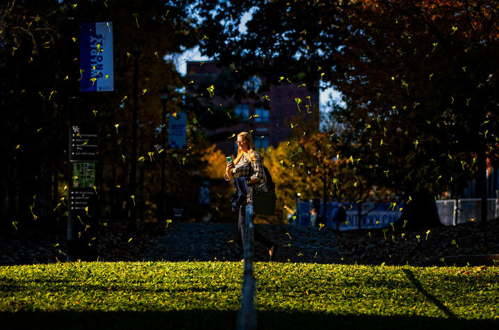 UK student surrounded by falling gingko leaves on campus