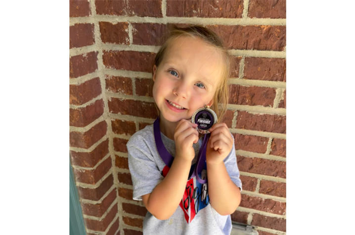 image of Faye holding her race medal