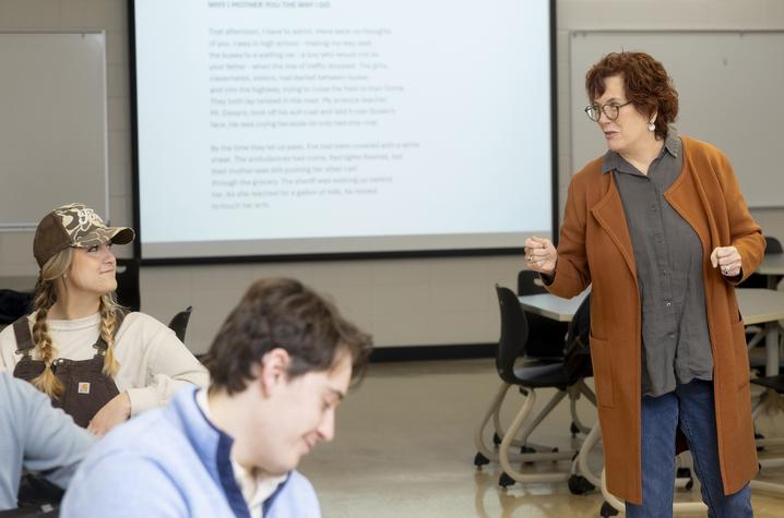 photo of a creative writing workshop for students Two students sitting in a classroom while being addressed by a professor