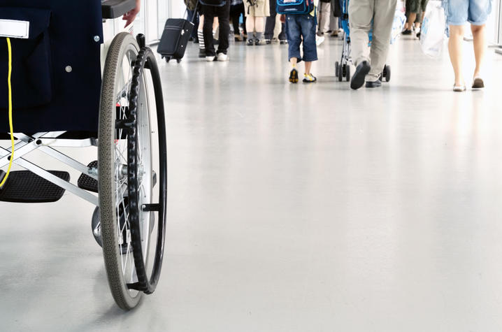 A person in a wheelchair is being pushed through a busy airport setting.