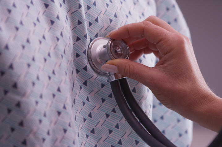 A health care provider places a stethoscope against the chest of a person wearing a hospital gown. A health care provider places a stethoscope against the chest of a person wearing a hospital gown.