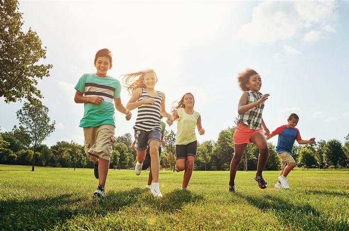 Photo of children running outside Five children running outside on the grass