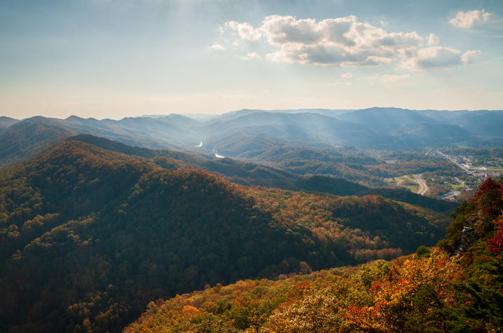 Eastern Kentucky A panoramic view of forested Appalachian mountains covered in fall foliage, with a valley and community visible in the distance.