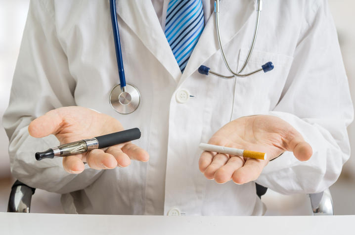 photo of a doctor holding a vape pen and a cigarette