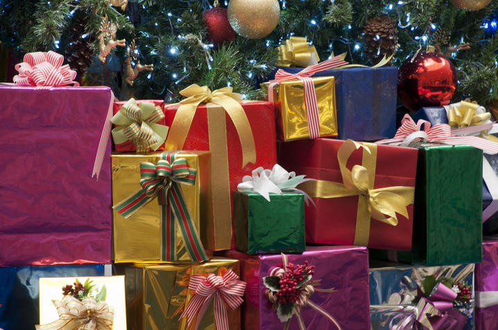 Photo of a pile of wrapped gifts by Christmas tree