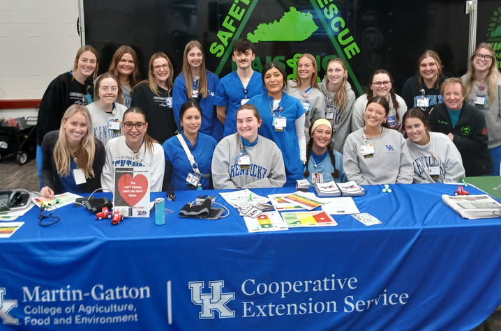 photo of students in rural health clinical rotation A large group of people gather behind an event table covered with a blue cloth displaying “UK Cooperative Extension Service” and “Martin‑Gatton College of Agriculture, Food and Environment.”