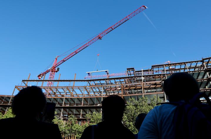 a large crane lifts the final steel beam into place at the new HEB building