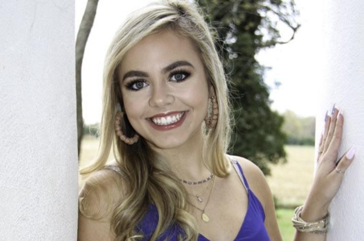 headshot photo of Haley Shaver standing outside between 2 columns