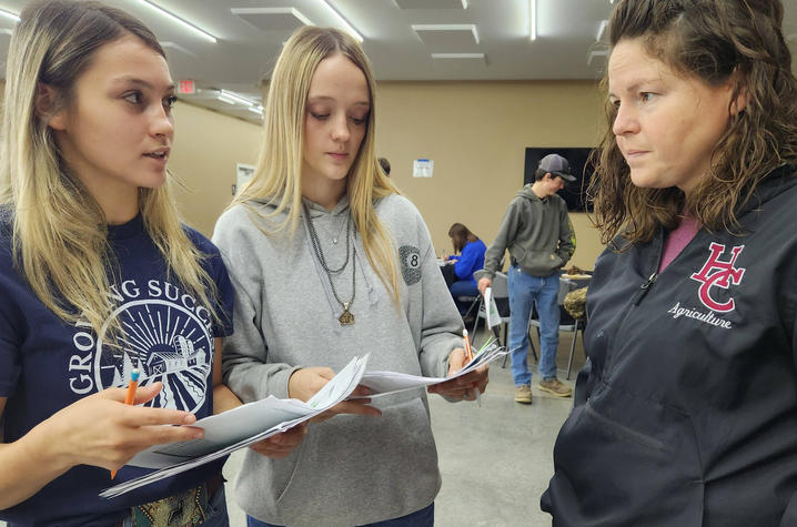 photo of agriculture teacher talking with students Two students standing across from adult teacher while having a conversation