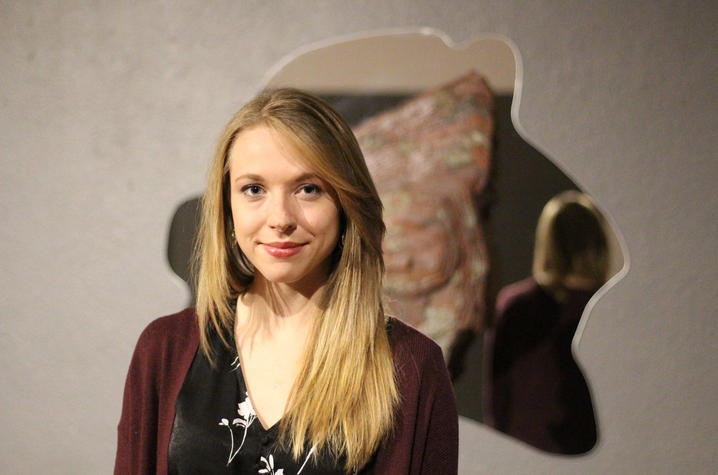 Person standing in front of an abstract wall sculpture.