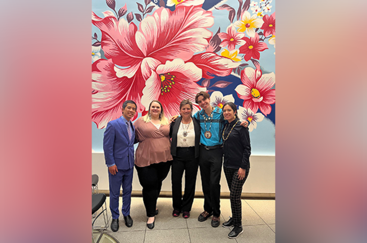 Mixed group of five people standing in front of a flower mural.