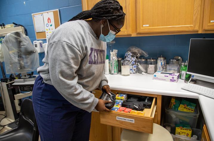 Image of DeAsia King checking supplies in a drawer labeled "pediatric clinic"