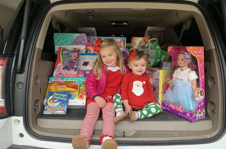 image of Harper sitting in a car filled with toys to donate to the hospital