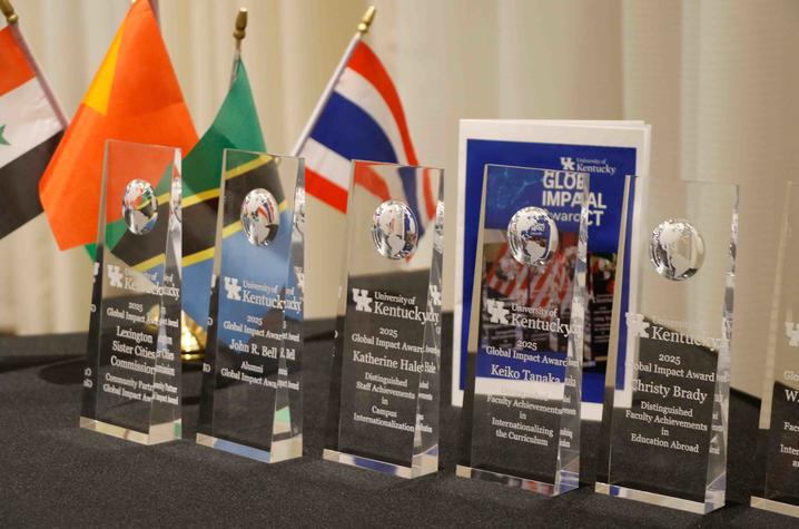 University of Kentucky 2025 Global Impact Award trophies displayed on a table with international flags behind them.