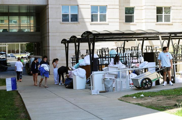 Students move belongings and furniture outside a residence hall during campus move-in.