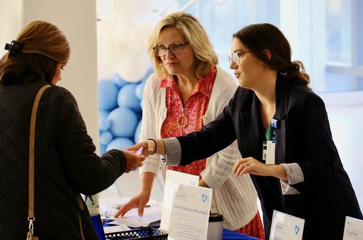 Two women handing out flyers to a third woman