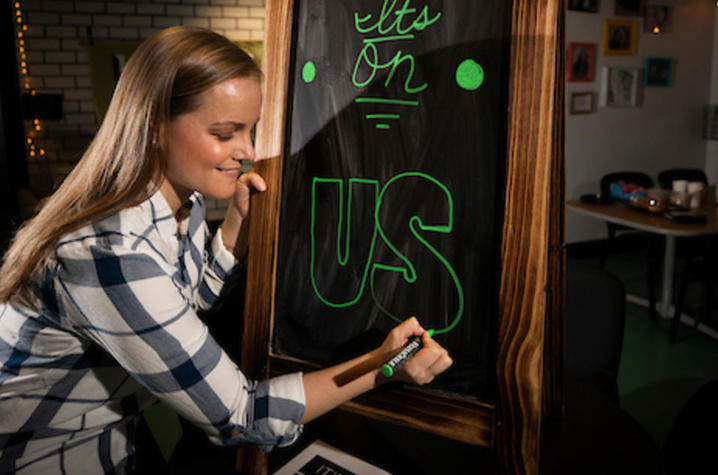 Photo of Lenzi Dodgen Writing “It’s on Us” on Chalkboard. 