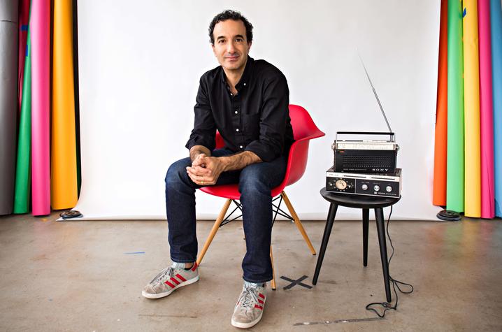 photo of Jad Abumrad seated in red chair next to radio