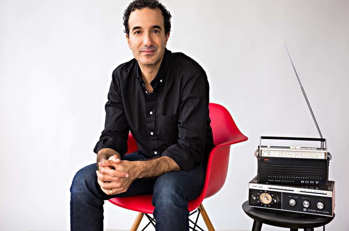 photo of Jad Abumrad seated in red chair next to radio