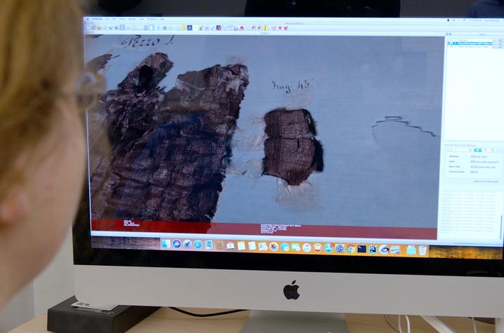 This is a photo of a masters student, studying digital images of a damaged manuscript.
