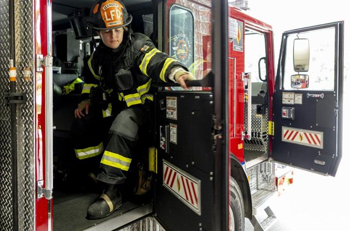 Firefighter wears LION's turnout gear on firetruck.