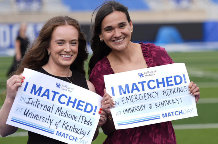 Photo of UK College of Medicine students Two people stand outdoors holding matching signs that read “I MATCHED!” One sign says “Internal Medicine — University of Kentucky,” and the other says “Emergency Medicine — University of Kentucky,” with “MATCH” printed at the bottom.