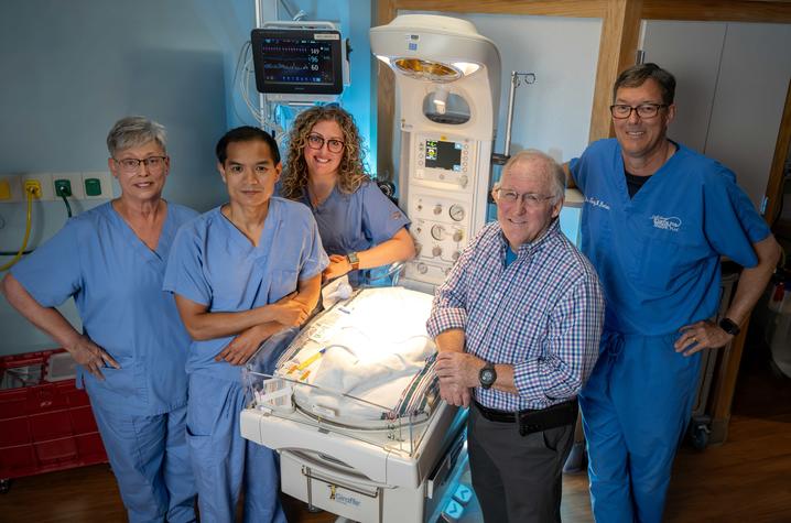 Image of providers standing around a hospital bassinett