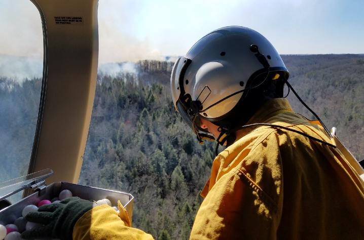 Photo of Becky Parsley performing aerial ignition from a helicopter