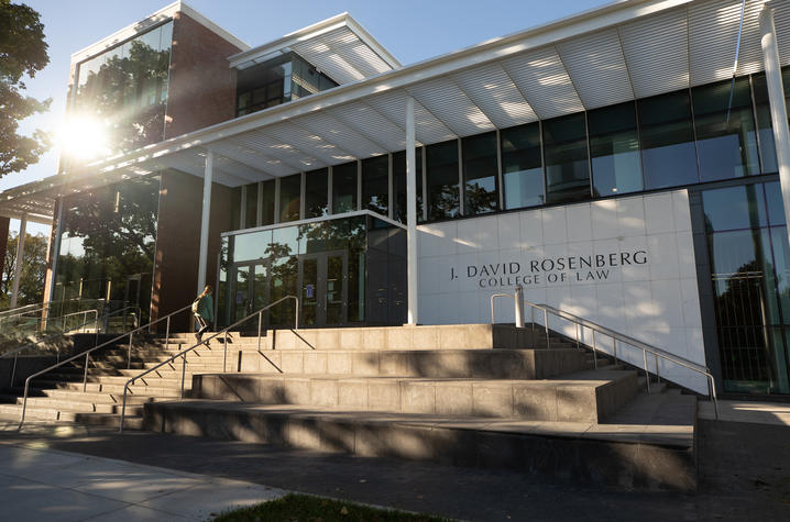 photo of front of the Rosenberg College of Law Building and a student walking up the steps