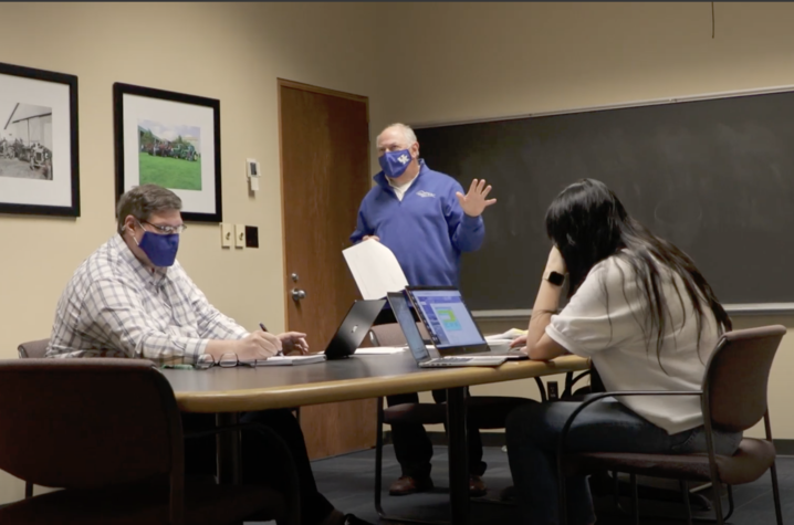 Wayne Sanderson in background of classroom with two students