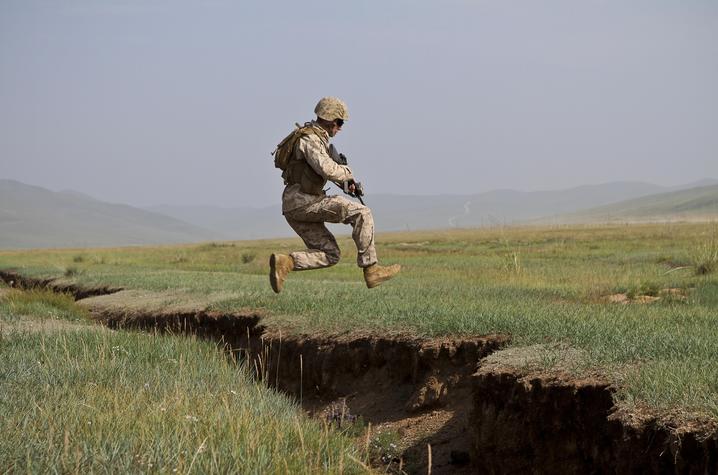 U.S. Marine Lance Cpl. Nicholas Moore  jumps over a ditch during a cordon and search lane. Photo By Cpl. Robert Bush