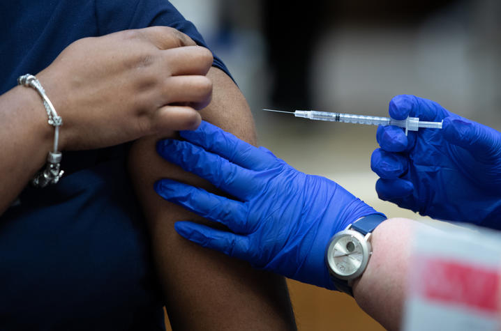 person in latex gloves administers covid 19 vaccine shot in arm to UK HealthCare employee.