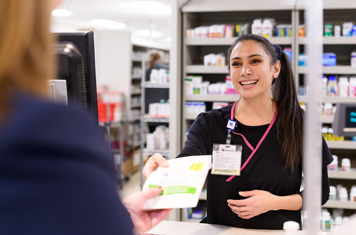 Pharmacist smiling and handing medication to customer