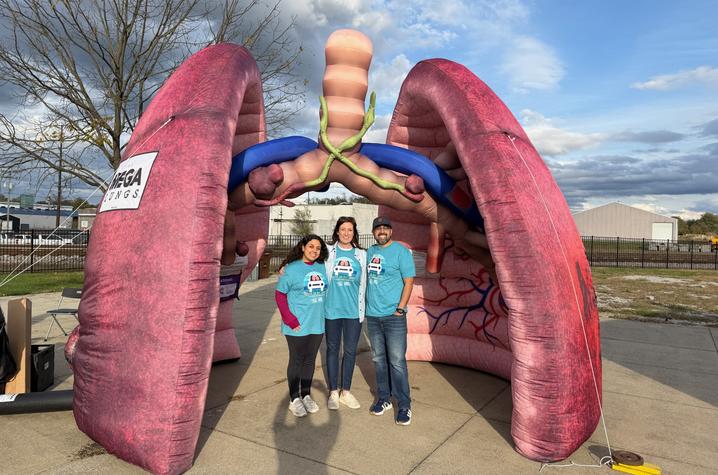 Three people standing in front of an inflatable lung. 