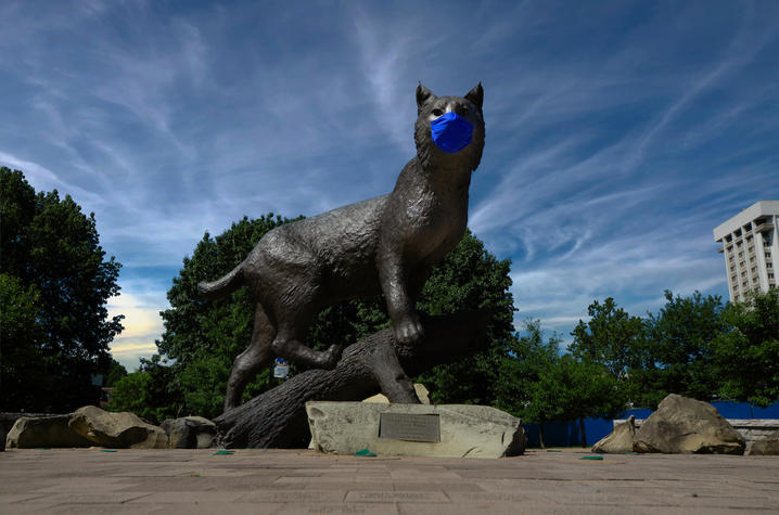 photo of statue of Bowman at the Wildcat Alumni Plaza. He is wearing a covid-19 mask.