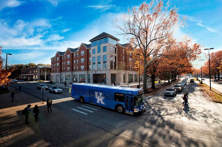 photo of bus passing by residence hall with fall trees