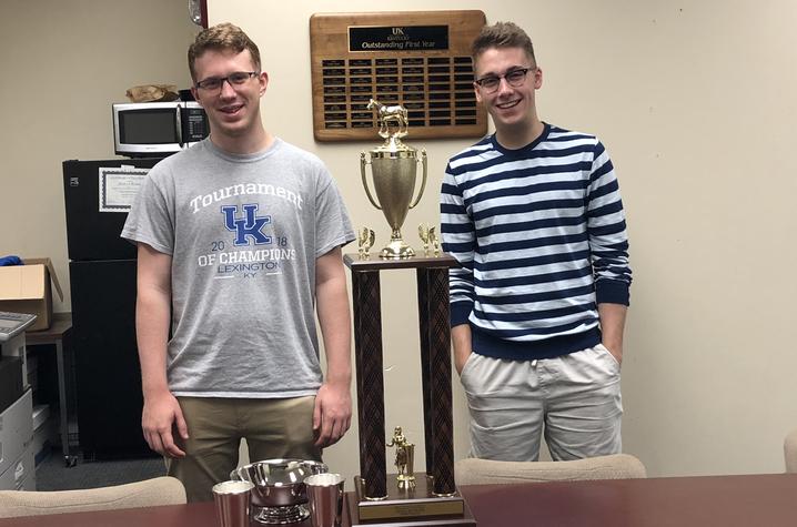 two guys standing with a trophy 