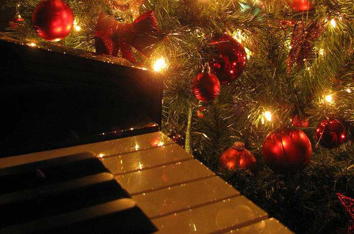 photo of Christmas tree with red ornaments and musical symbols next to piano