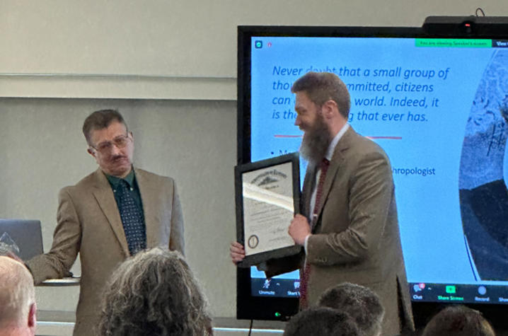 Image of Dr. Kanga being presented with a framed award