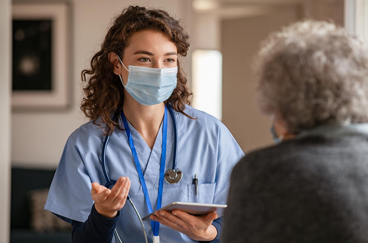 Doctor visits woman with surgical mask.