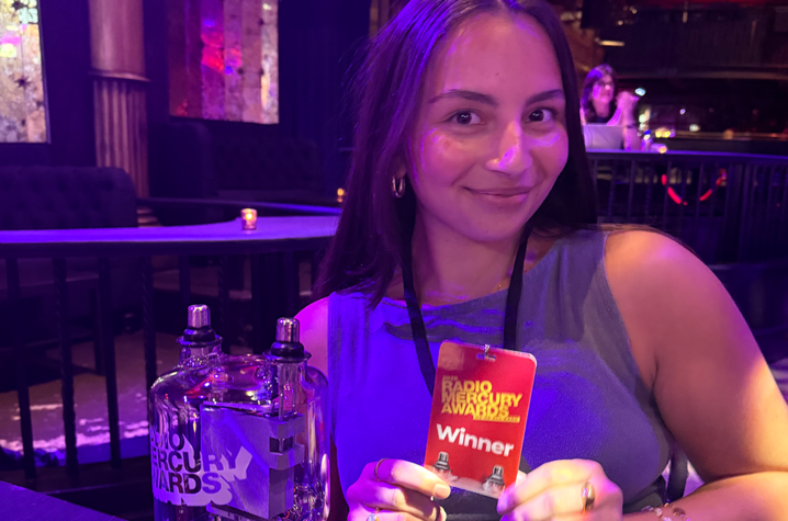 Person holding a card at a table in a purple-lit restaurant, with bottles and a beverage in the foreground.