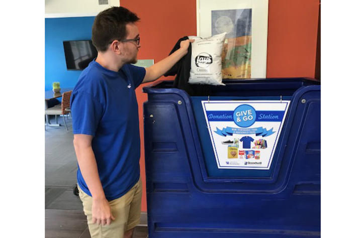 photo of person putting bag in recycling bin