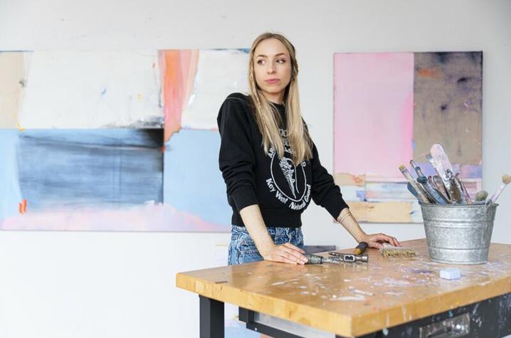 photo of Dana James in her studio with paintings behind her