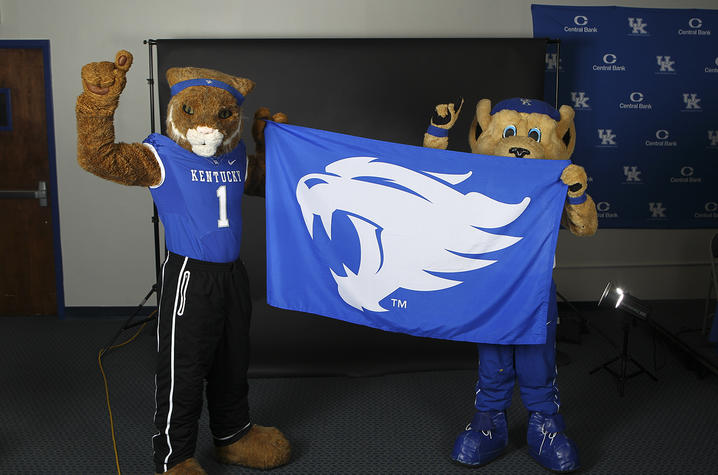 photo of UK mascots holding flag with UK Wildcat photo on it