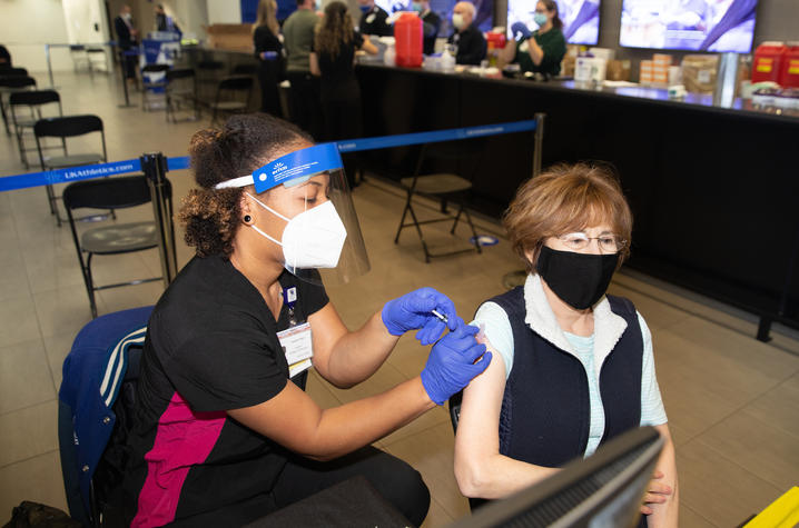 woman receives covid shot in her left arm at UK vaccination clinic