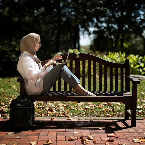 Student sits on bench on campus