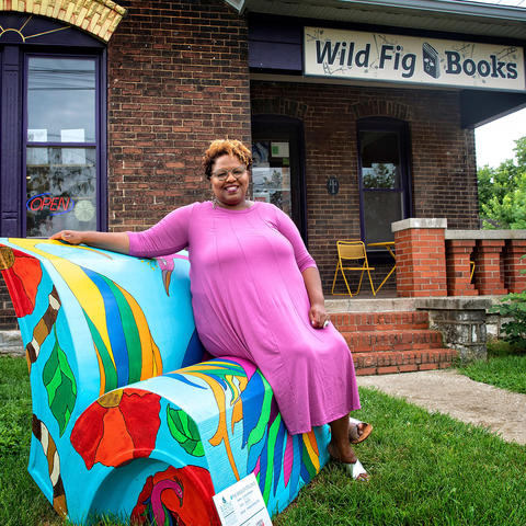 photo of Crystal Wilkinson seated on her book's bench outside Wild Fig