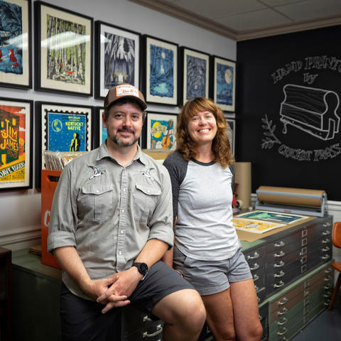 Brian and Sara Turner at Cricket Press in front posters of their work