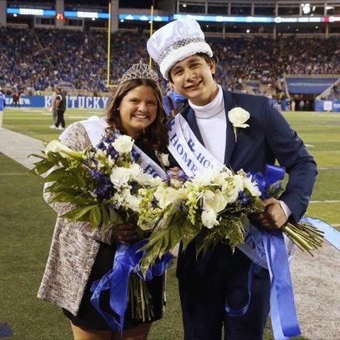 Gracelyn Bush and Johnny Zelenak II in homecoming crowns and sashes with flowerss